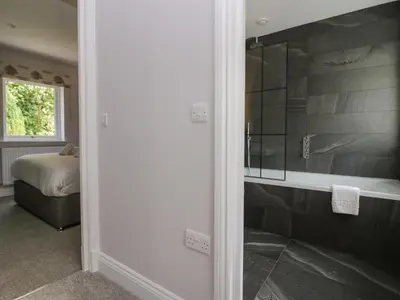 a bathroom with a glass shower and a bed at Garden Cottage No 1 in Keswick