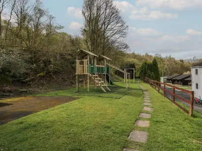 a playground in the grass next to a fence at Garden Cottage No 1 in Keswick