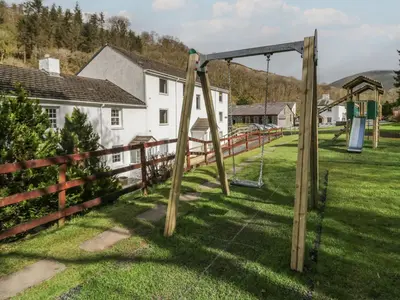 a swing set in a yard next to a fence at Garden Cottage No 1 in Keswick