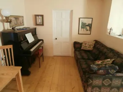 a living room with a couch and a piano at Threecrofts Farm in Dumfries