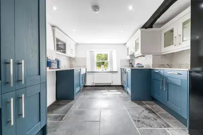 a large kitchen with blue cabinets and a window at Knott House Farm in Keswick