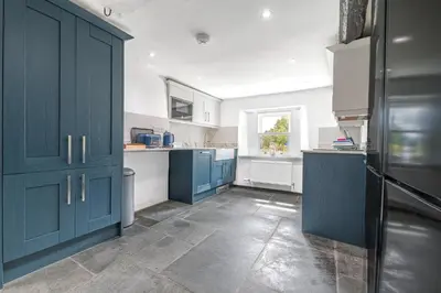 a large kitchen with blue cabinets and a window at Knott House Farm in Keswick