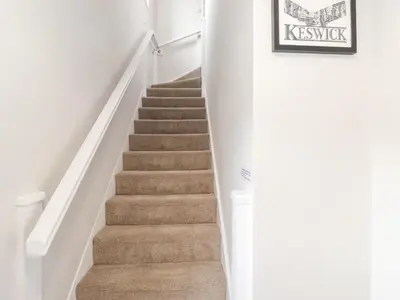 a staircase in a home with white walls and carpet at 1 Millbank in Keswick