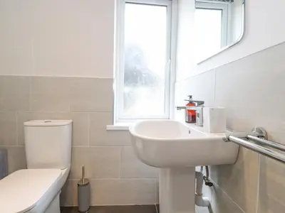 a bathroom with a sink and a toilet and a window at 1 Millbank in Keswick