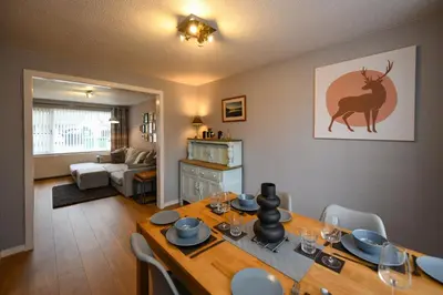 a living room with a table with a deer on the wall at Links Golf Villa in Troon