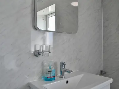 a white bathroom with a sink and a mirror at Montys in Castle Douglas