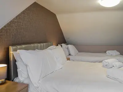 a bedroom with two beds with white sheets and towels at Montys in Castle Douglas