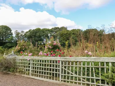 a fence in a garden with flowers at The Pavillion in Carlisle