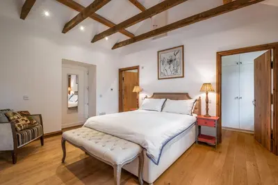 a bedroom with a large bed and a chair at Kilnmark Bothy in Thornhill