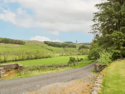 a road in the middle of a green field at Kilnmark Bothy in Thornhill