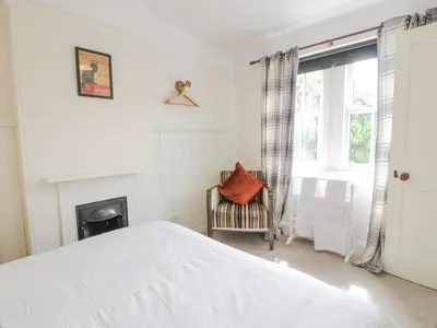 a white bedroom with a bed and a fireplace at High Auchenbrack in Thornhill