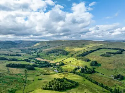 an aerial view of a valley in the hills at High Auchenbrack in Thornhill