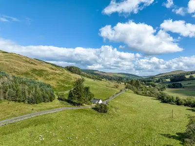 a grassy hill with a road in a field at High Auchenbrack in Thornhill