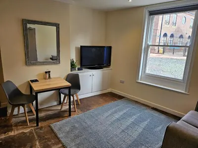 a living room with a table and a tv and a window at Carlisle City Centre The Gavel in Carlisle