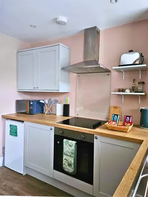 a kitchen with white cabinets and a stove top oven at The Ferns - Modern Apartment With Parking & Shared Garden in Darvel