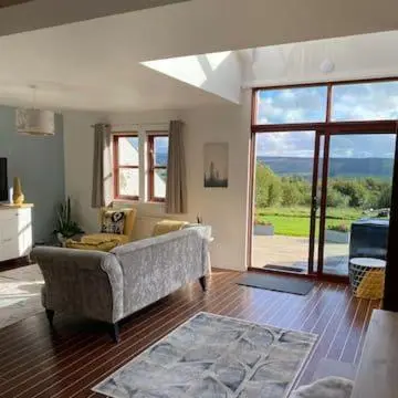 a living room with a couch and a large window at Lanfine View 1 at Loudoun Mains with Hot Tub in Newmilns