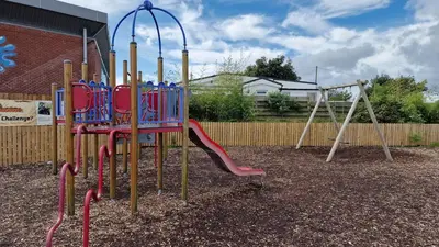 a playground with a slide and a swing at Seaside Heaven - Southerness Caravan Rental in Mainsriddle