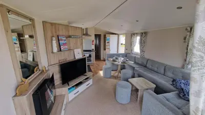 a living room with a couch and a tv at Seaside Heaven - Southerness Caravan Rental in Mainsriddle
