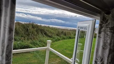 a view of the ocean from a window at Seaside Heaven - Southerness Caravan Rental in Mainsriddle