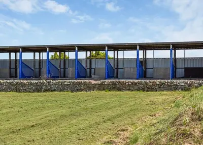 a building with blue posts and a grass field at Brighouse Bay Holiday Park in Kirkcudbright