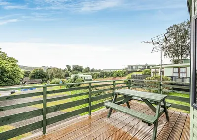 a wooden deck with a picnic table on top of it at Kippford View Holiday Park in Castle Douglas