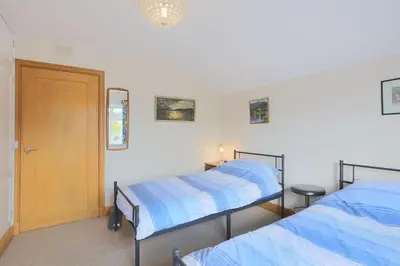 two beds in a room with a door and a window at Teapot Cottage in Newton Stewart