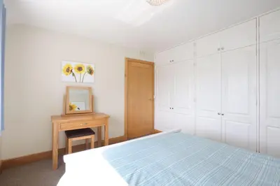 a bedroom with a bed and a table with a mirror at Teapot Cottage in Newton Stewart