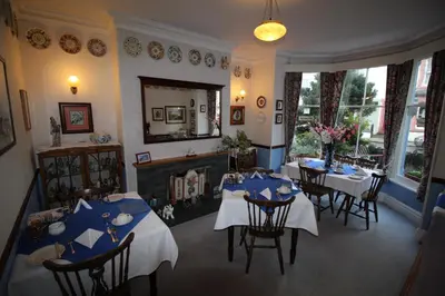 a dining room with tables and chairs and a fireplace at Bluestones in Keswick
