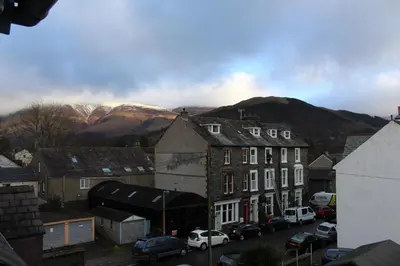 a town with cars parked in front of buildings and mountains at Bluestones in Keswick