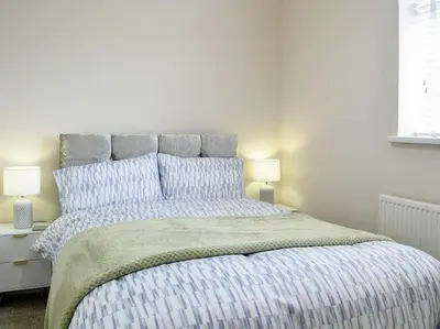 a white bedroom with a large bed with blue pillows at Paxville in Gretna