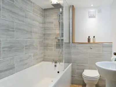 a bathroom with a tub and a toilet and a sink at Criffel Cottage in Ruthwell