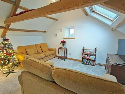 a living room with a couch and a christmas tree at Criffel Cottage in Ruthwell
