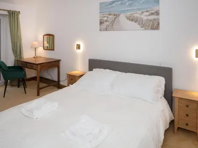 a bedroom with a white bed with a desk and a desk at Criffel Cottage in Ruthwell