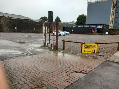 a parking lot with a yellow sign on a fence at The Lowther Penthouse - 2 Bedrooms - Sleeps 4 in Whitehaven