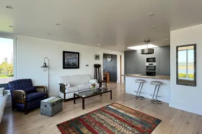 a living room with a couch and a table at Shorepark - waterfront cottage with stunning views in Dumfries