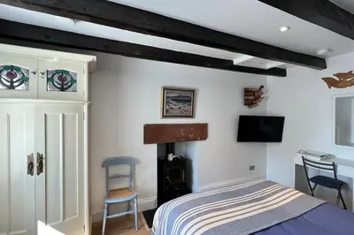 a bedroom with a bed and a desk and a tv at Shorepark - waterfront cottage with stunning views in Dumfries