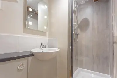 a white bathroom with a sink and a shower at Goody Bridge Barn in Grasmere