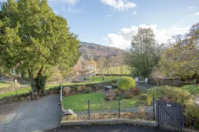 a gate to a garden with a hill in the background at Goody Bridge Barn in Grasmere