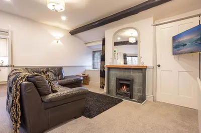 a living room with a couch and a fireplace at Goody Bridge Barn in Grasmere
