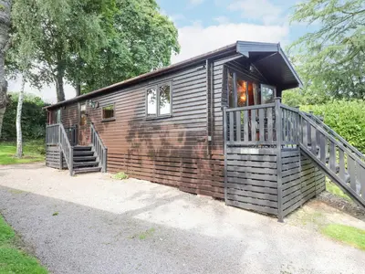a wooden cabin with a porch and a staircase at Ennerdale Lodge in Keswick