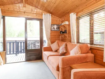 a living room with a couch and a balcony at Ennerdale Lodge in Keswick