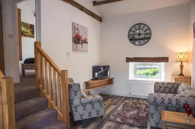 a living room with stairs and a clock on the wall at The Hidden Place in Penrith