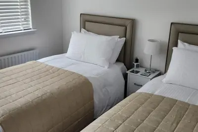 a hotel room with two beds and a table with a lamp at 10 Ladyknowe court in Moffat