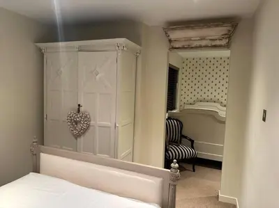 a bedroom with a white cabinet and a mirror at Bonshaw Grange-Riverside Country Retreat, & HotTub in Lockerbie