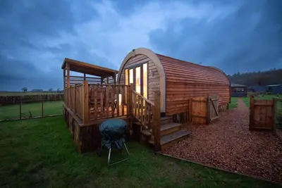 a large wooden cabin with stairs and a chair at The Galloway Steading - The Herons Nest, secure garden and with Hot Tub and Fire Pit in Glenluce