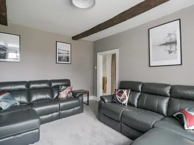 a living room with a leather couch and a table at The Hollies in Carlisle