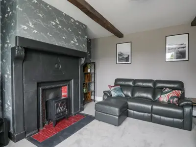 a living room with a black fireplace and a leather couch at The Hollies in Carlisle