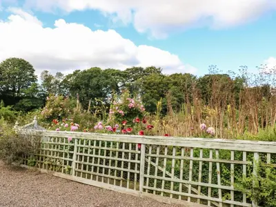 a fence in a garden with flowers at The Courtyard in Carlisle