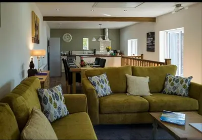 a living room with a couch and a kitchen at Church House Barn Lake District & Solway Coast with Solway Firth views in Silloth