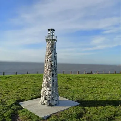 a stone lighthouse sitting in a field of grass at Church House Barn Lake District & Solway Coast with Solway Firth views in Silloth